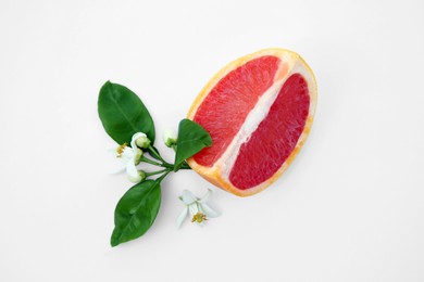 Photo of Cut fresh ripe grapefruit and green leaves on white background, top view
