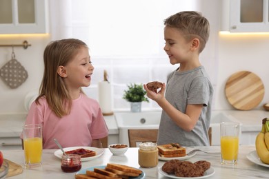 Little children having fun during breakfast at table in kitchen