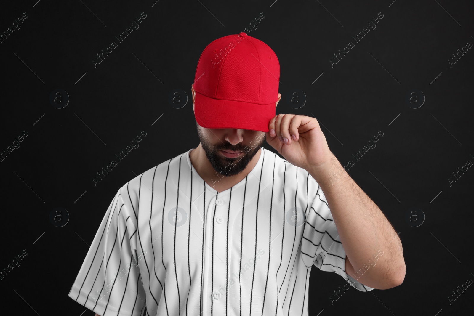 Photo of Man in stylish red baseball cap on black background