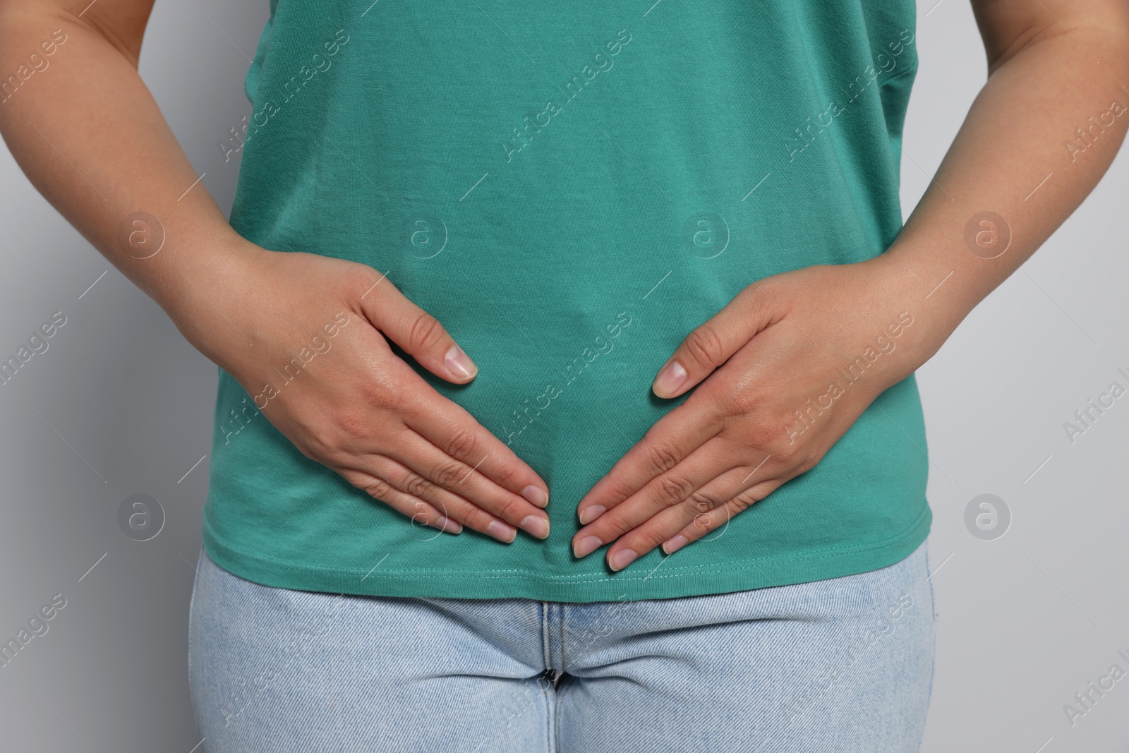 Photo of Young woman suffering from menstrual pain on grey background, closeup