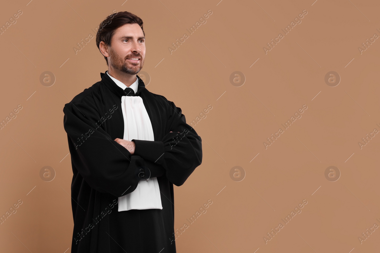 Photo of Smiling judge with crossed arms on light brown background. Space for text