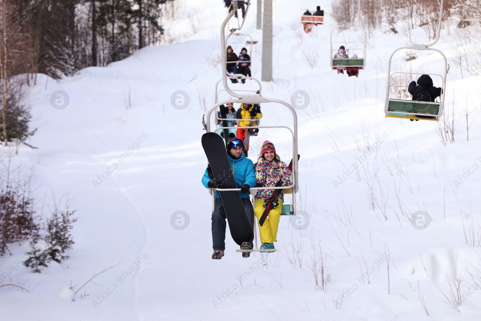 Photo of Couple using chairlift at mountain ski resort. Winter vacation