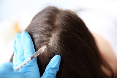 Photo of Young woman with hair loss problem receiving injection in clinic