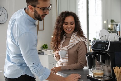 Photo of Man talking with colleague while using modern coffee machine in office