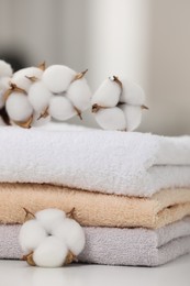 Photo of Terry towels and cotton branch with fluffy flowers on white table, closeup