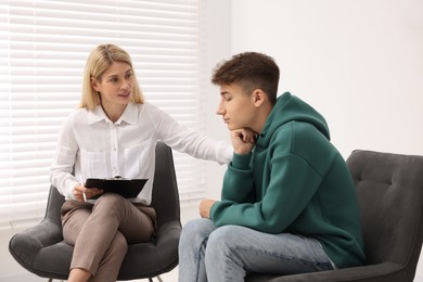 Psychologist working with teenage boy in office