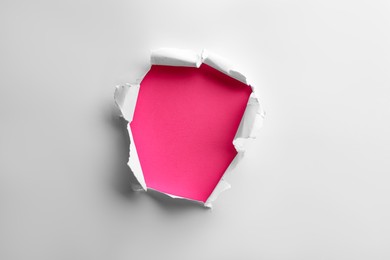 Photo of Hole in white paper on pink background