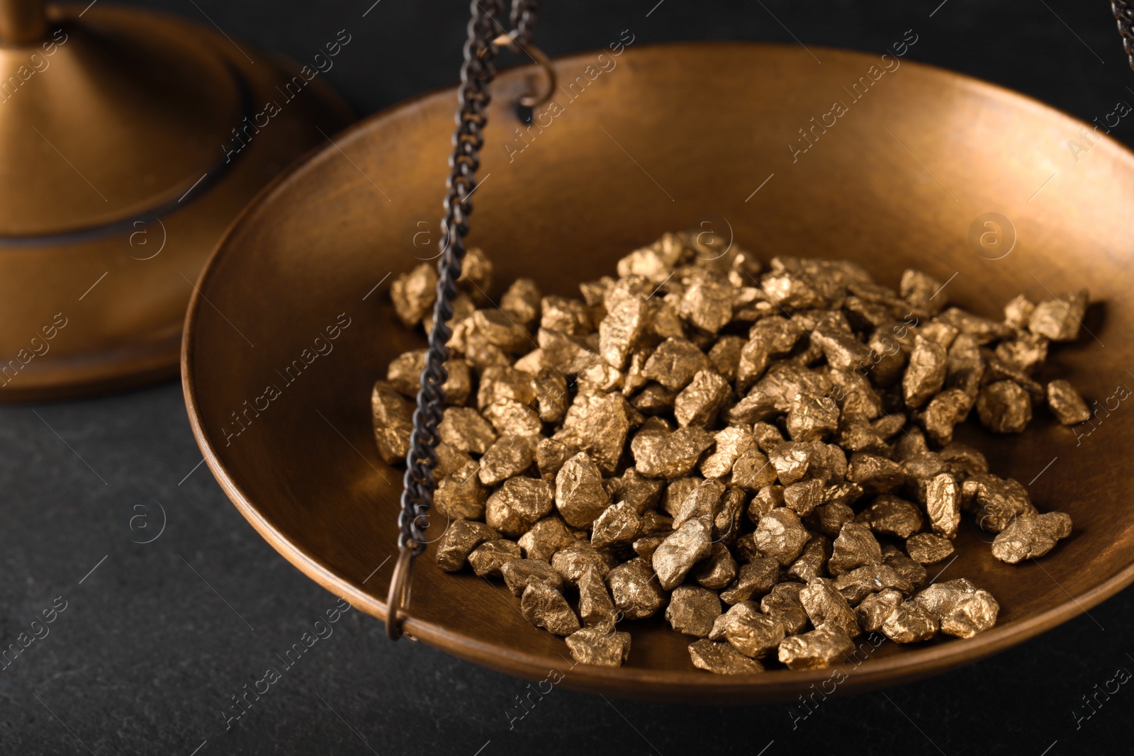 Photo of Vintage scales with gold nuggets on dark table, closeup