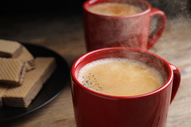 Photo of Delicious coffee and wafers on wooden table, closeup