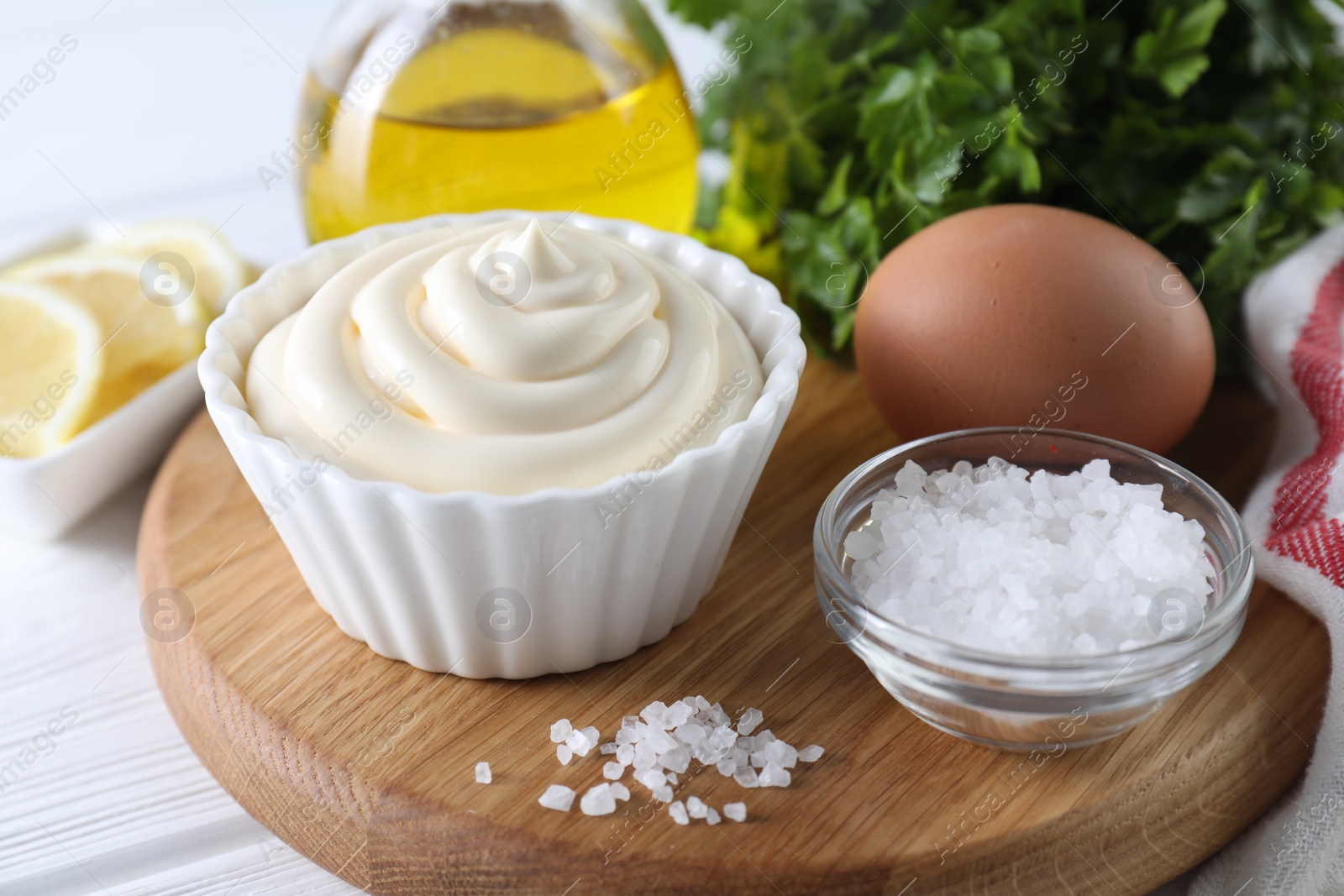 Photo of Fresh mayonnaise sauce in bowl and ingredients on table, closeup