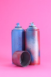 Spray paint cans with cap on pink background