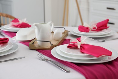 Photo of Color accent table setting. Plates, cutlery and pink napkins, closeup