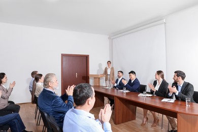 People applauding to speaker at business conference in meeting room