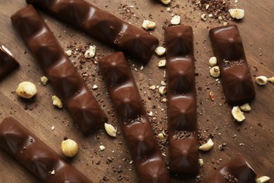 Tasty chocolate bars with nuts on wooden table, flat lay