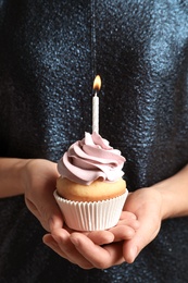 Photo of Woman holding delicious birthday cupcake with burning candle, closeup