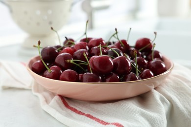 Photo of Fresh ripe cherries and towel on white table, closeup