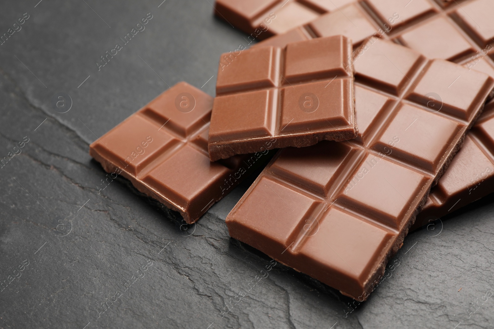 Photo of Delicious milk chocolate on black table, closeup