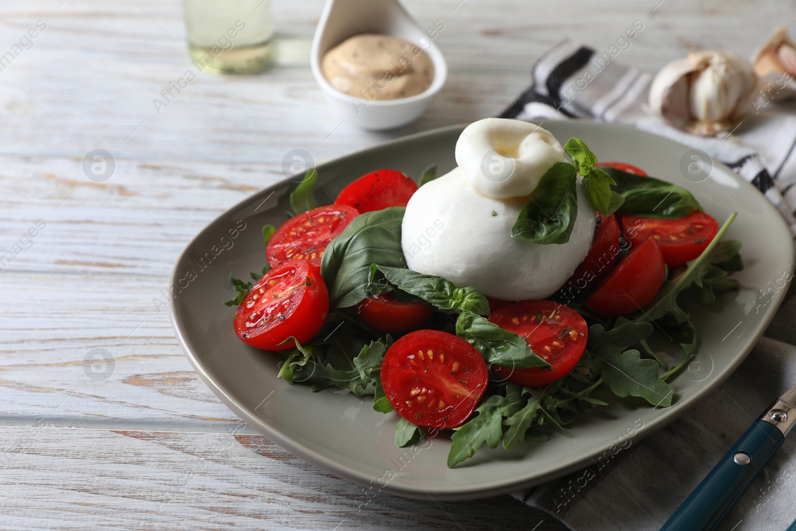 Photo of Delicious burrata cheese served with tomatoes and basil on white wooden table. Space for text