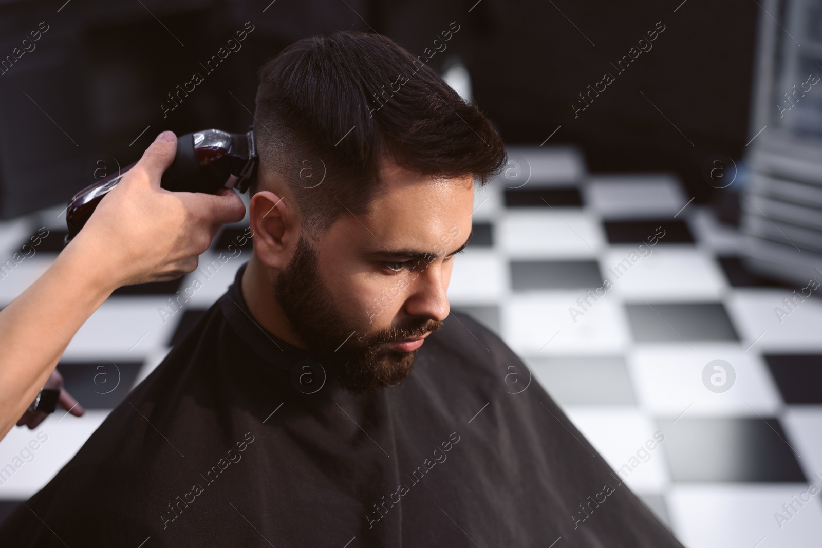 Photo of Professional hairdresser working with client in barbershop