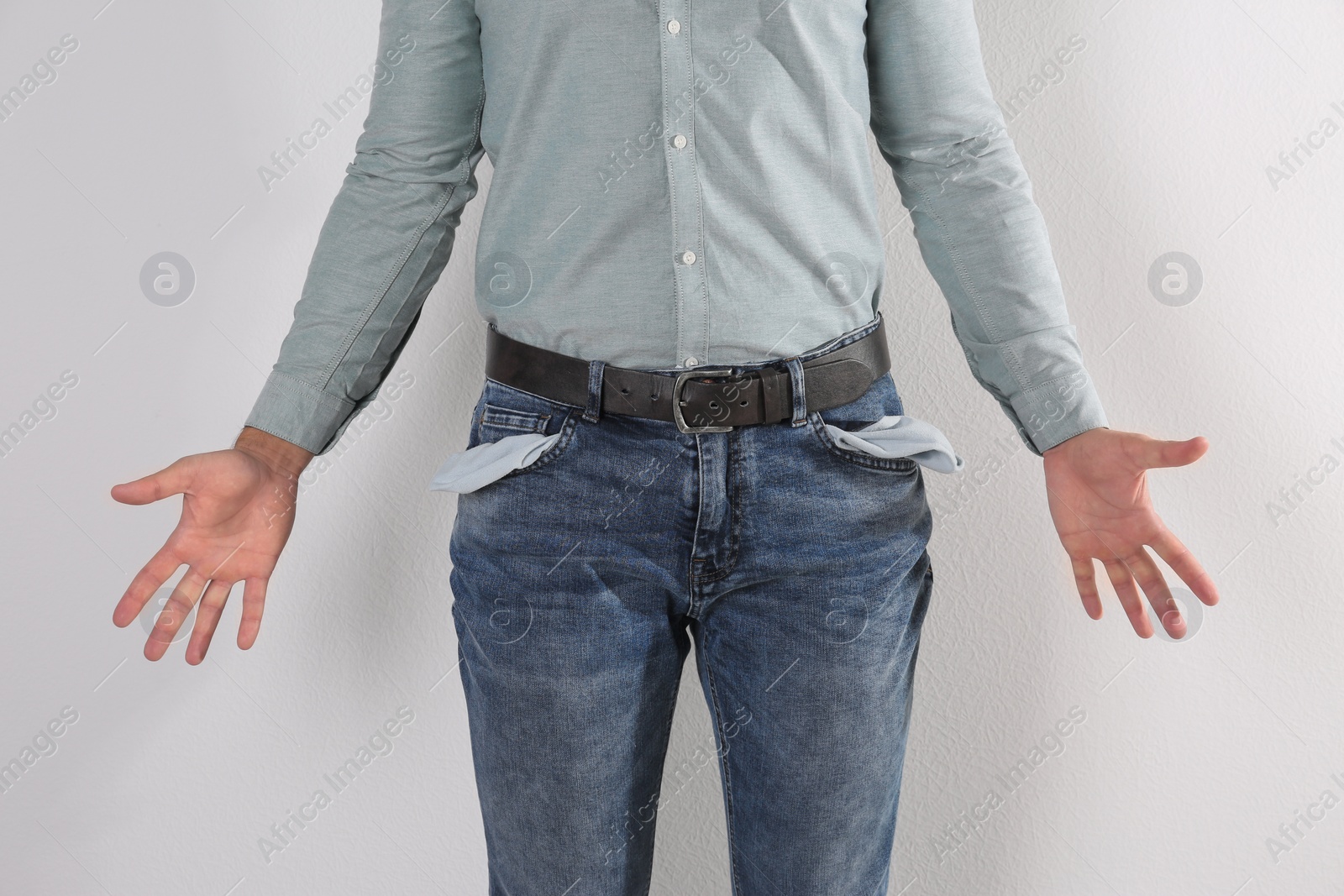 Photo of Man showing empty pockets on light background, closeup