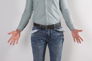 Photo of Man showing empty pockets on light background, closeup