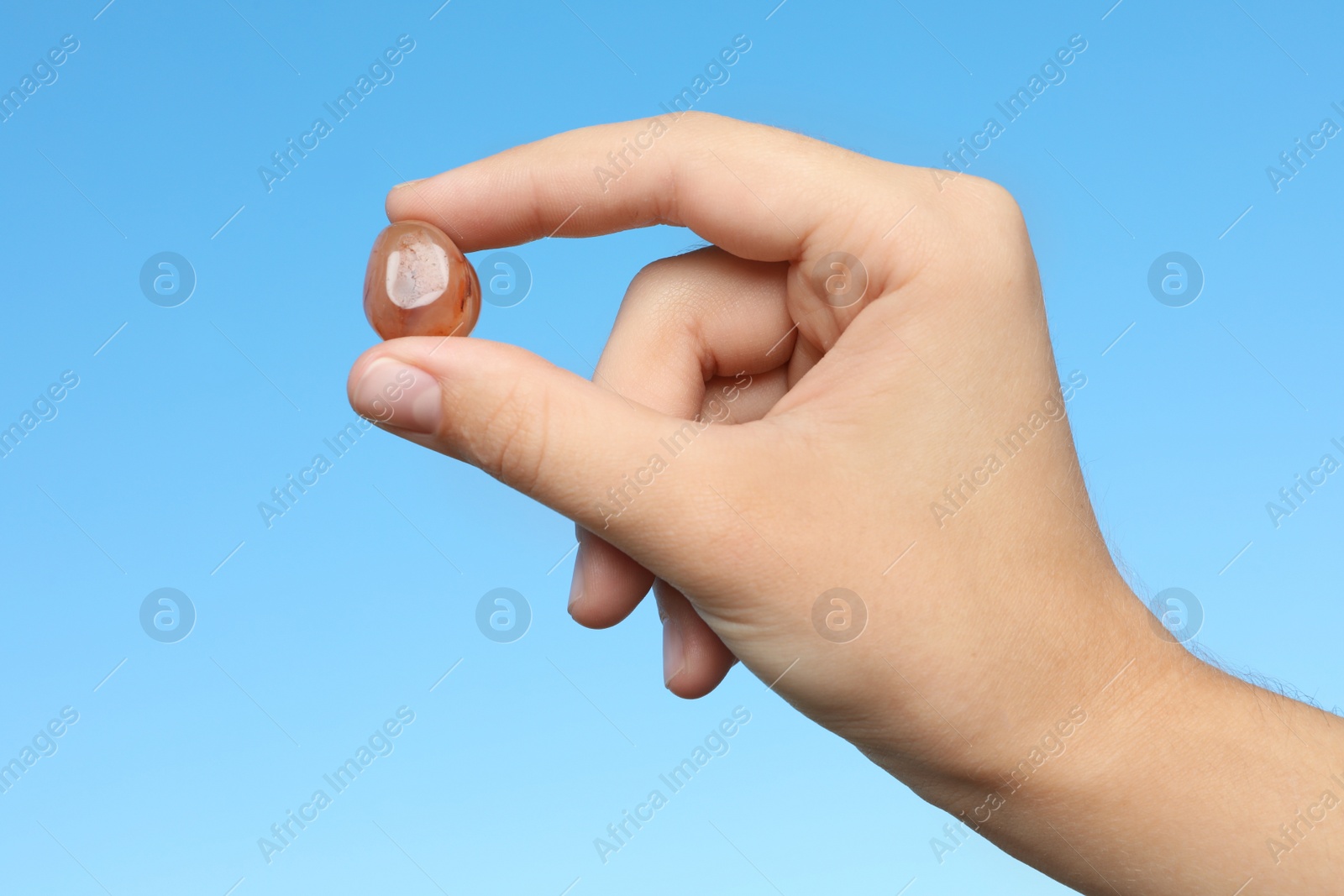 Photo of Woman holding agate gemstone against blue background, closeup