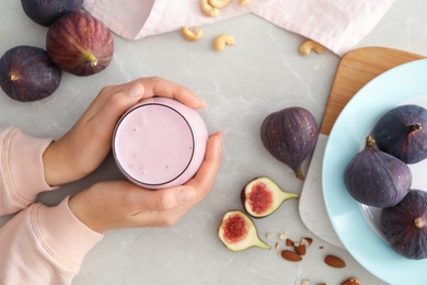 Woman with delicious fig smoothie at light table, top view