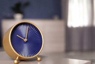 Analog alarm clock on table in living room. Time of day