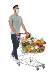 Man with protective mask and shopping cart full of groceries on white background