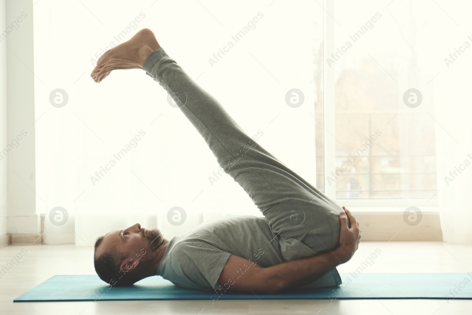 Photo of Sporty man practicing yoga indoors