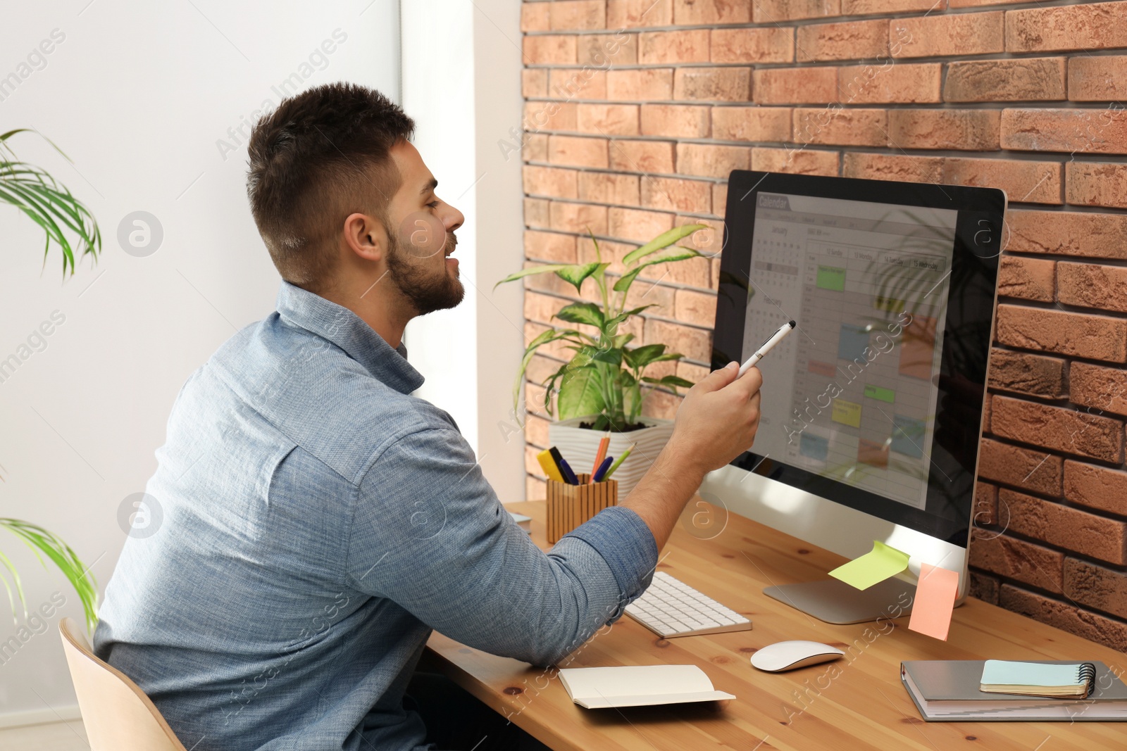 Photo of Young man using calendar app on computer in office