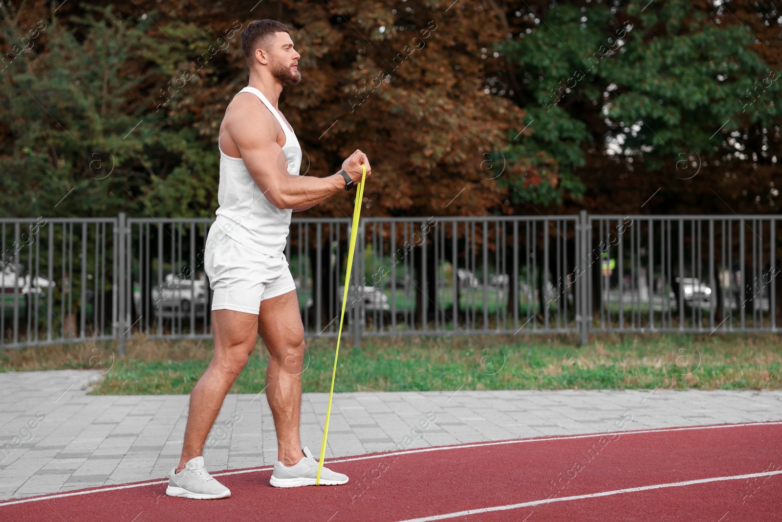 Photo of Muscular man doing exercise with elastic resistance band outdoors