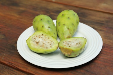 Tasty prickly pear fruits on wooden table