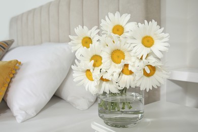 Bouquet of beautiful daisy flowers on table in bedroom, space for text