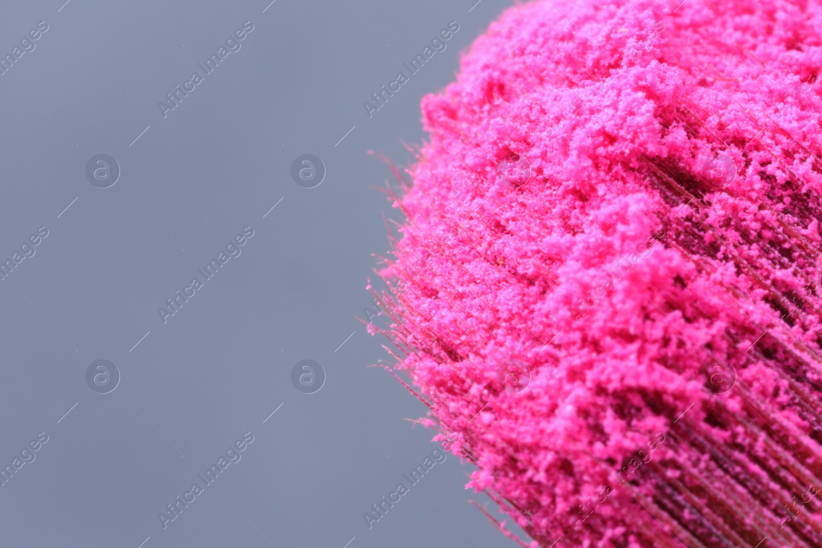 Photo of Makeup brush with pink eye shadows on grey background, macro view. Space for text