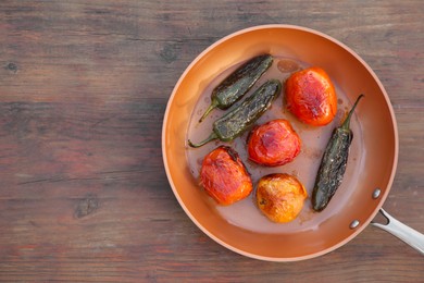 Frying pan with ingredients for salsa sauce on wooden table, top view. Space for text