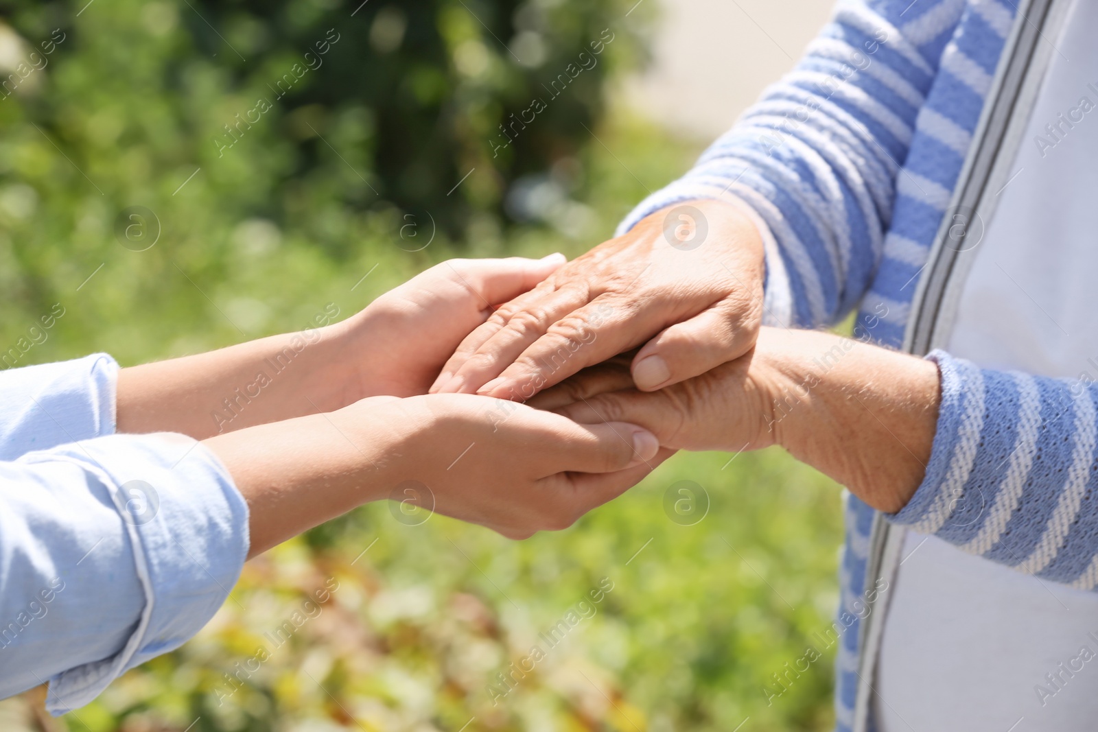 Photo of Helping hands on blurred background, closeup. Elderly care concept