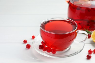 Tasty hot cranberry tea in glass cup and fresh berries on white table