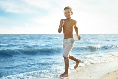 Photo of Cute African-American boy enjoying sunny day at beach. Summer camp