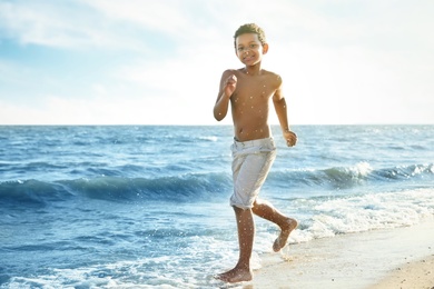 Cute African-American boy enjoying sunny day at beach. Summer camp