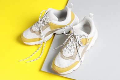 Stylish sneakers with shoe laces on color background