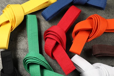 Photo of Colorful karate belts on gray background, flat lay