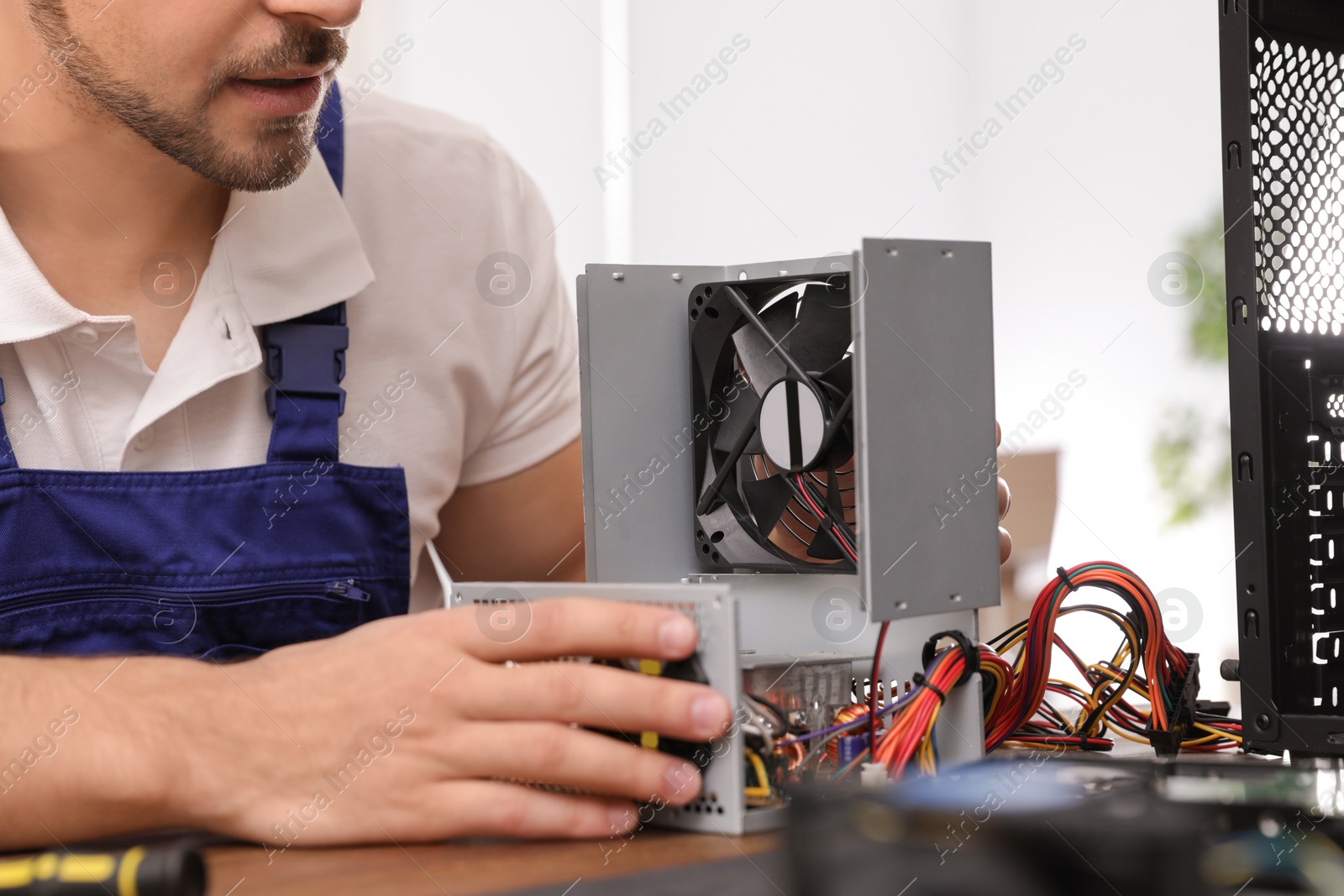 Photo of Male technician repairing power supply unit at table, closeup