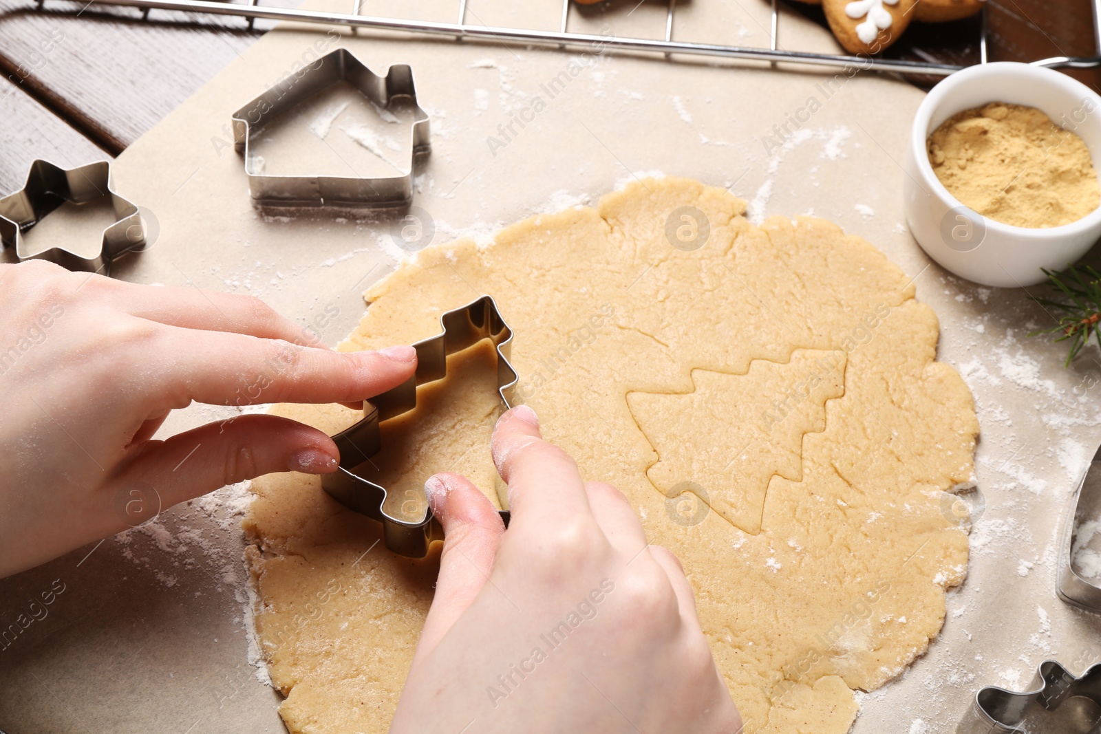 Photo of Woman making Christmas cookies with metal cutters at table, closeup