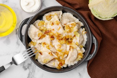 Photo of Cooked dumplings (varenyky) with tasty filling and fried onions on white marble table, flat lay
