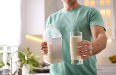 Photo of Man with gallon bottle of milk and glass in kitchen, closeup