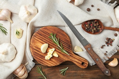 Photo of Flat lay composition with garlic, spice and rosemary on wooden background