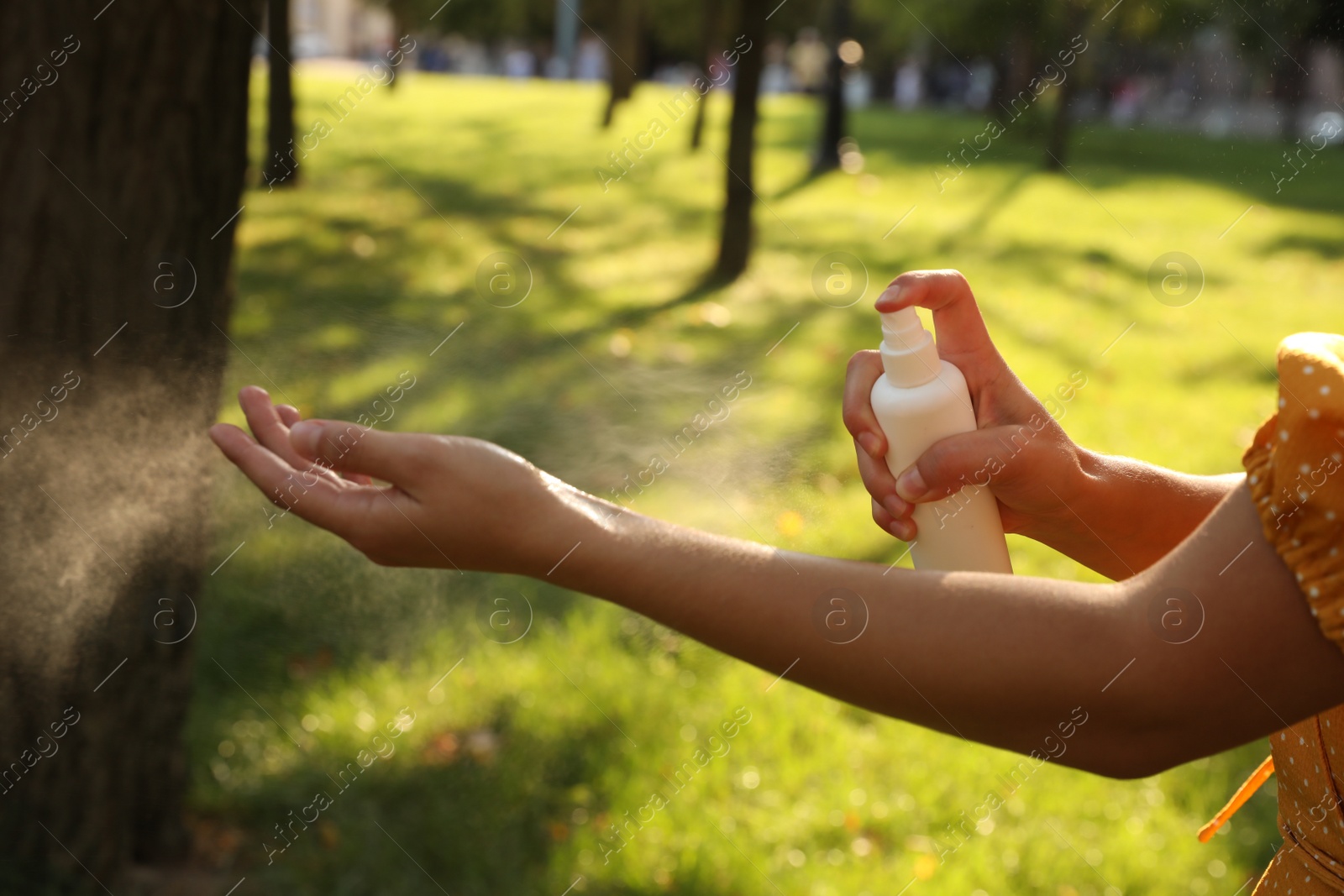 Photo of Woman applying insect repellent onto hand in park, closeup