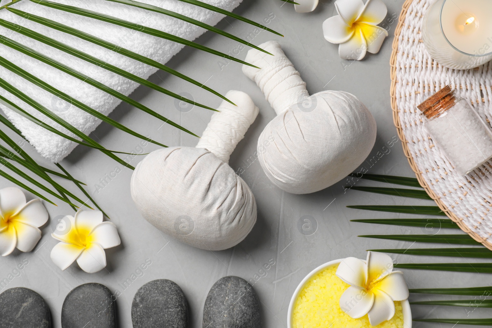 Photo of Spa bags, stones and orchid flowers on light gray table, flat lay