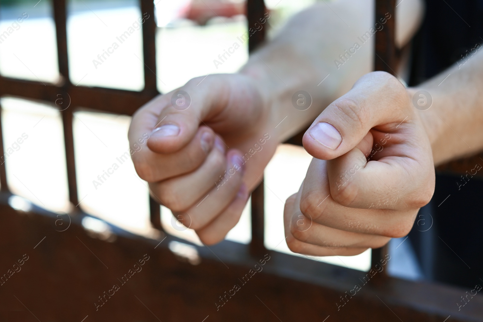 Photo of Man detained in jail outdoors, closeup. Criminal law